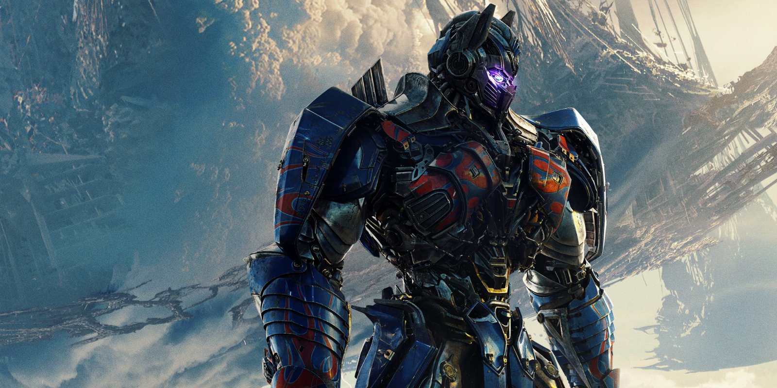 Armored Transformer from the movie Transformers: The Last Knight stands on a snowy ridge, blue-and-red battle-worn plating and glowing purple eyes against a stormy sky.
