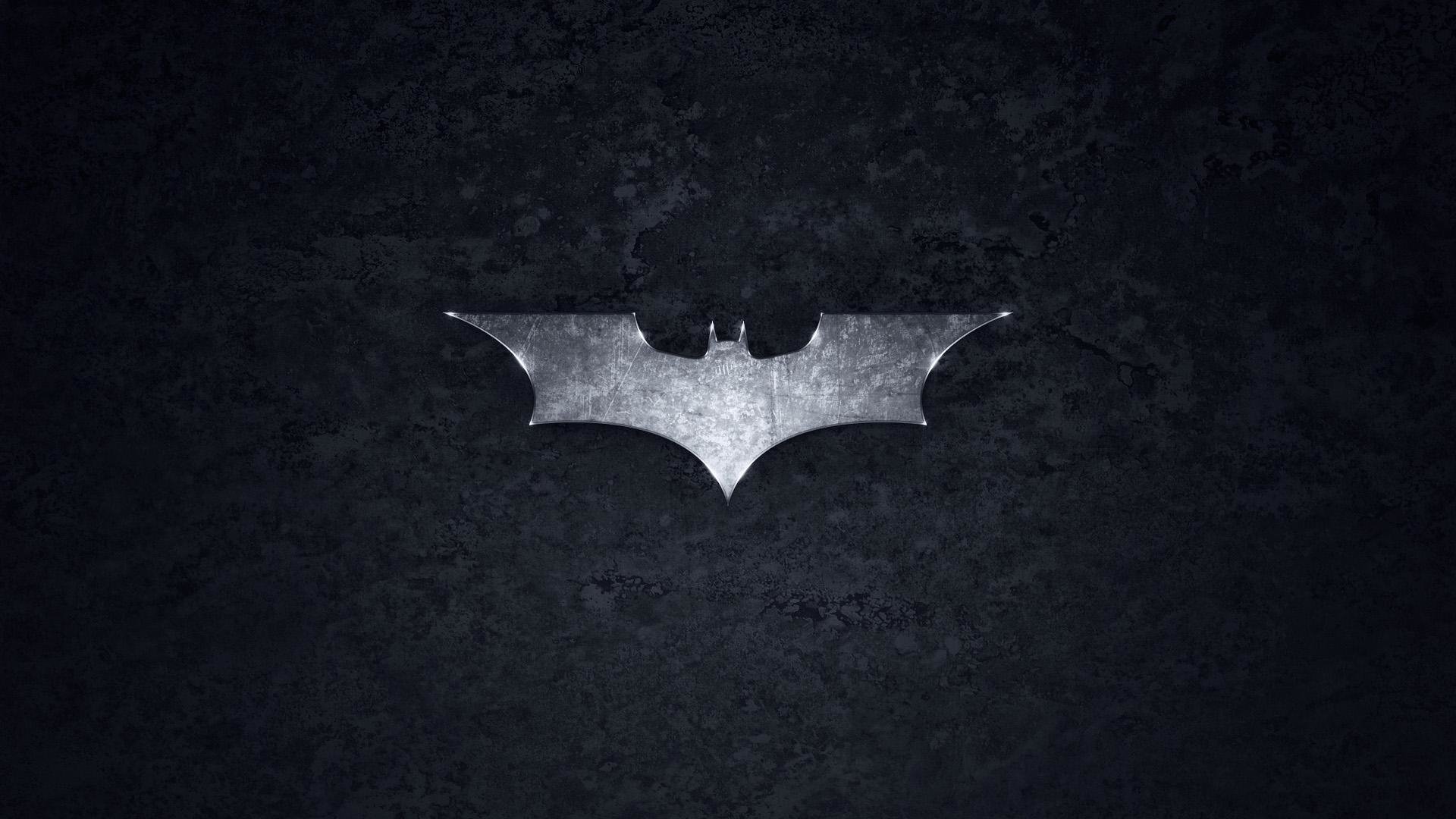 Silver Batman symbol centered on a textured black background, comic-style Batman logo.