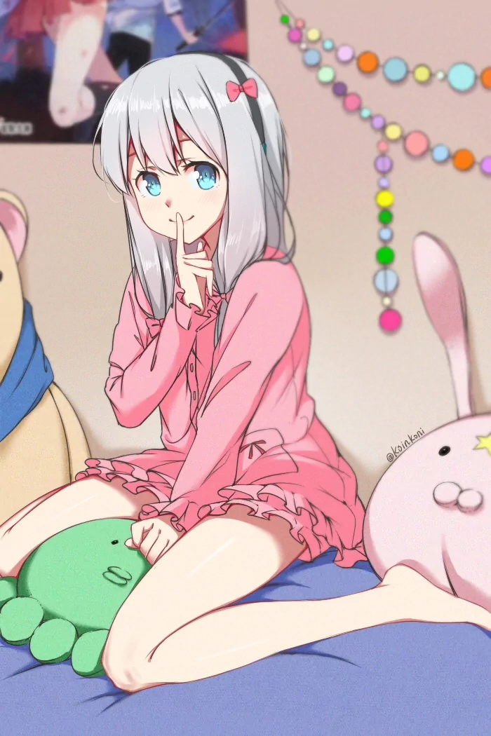 Anime character Sagiri Izumi from EroManga-Sensei sits on a bed in pink pajamas, silver hair and blue eyes, finger to her lips, surrounded by plush toys and pastel room decorations.