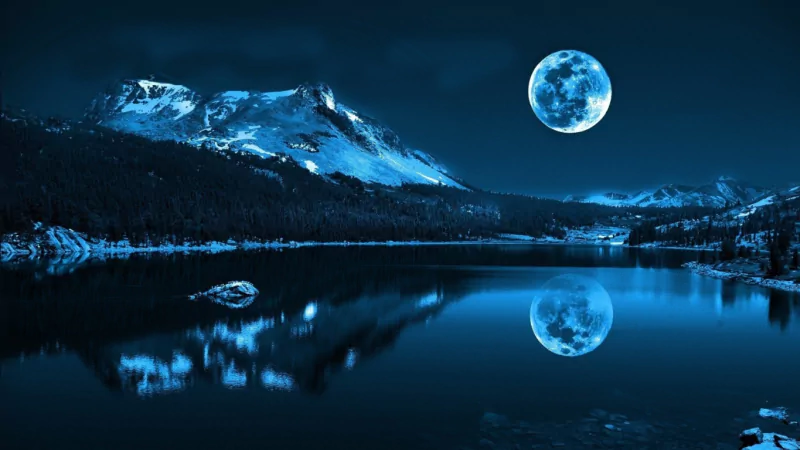 A serene night scene of nature featuring a bright full moon reflecting over a calm lake with snow-capped mountains in the background.