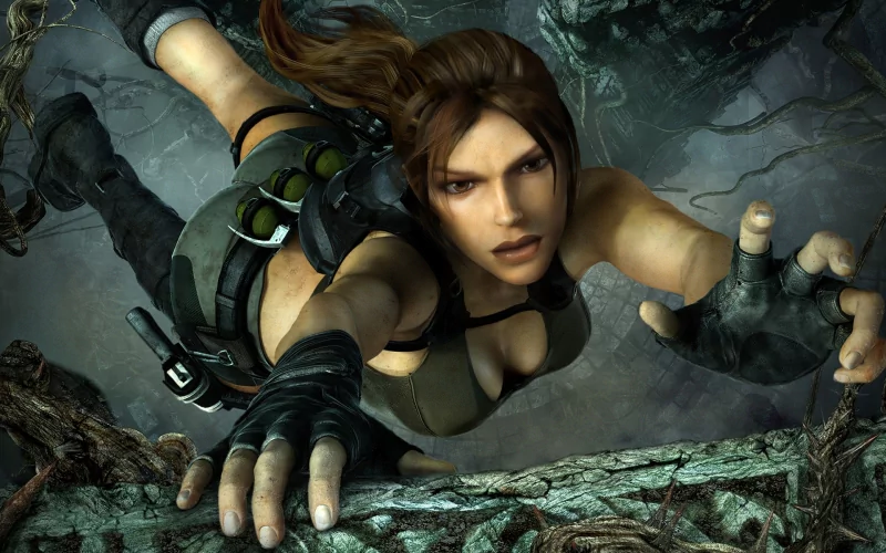 Lara Croft from the video game Tomb Raider: Underworld reaching out while climbing a rocky surface in a dark, intense environment.