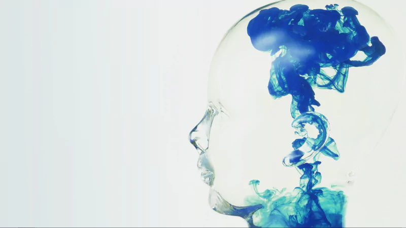 Abstract image of a translucent human head with blue diffusion-like ink swirling inside, blending art and scientific visualization.