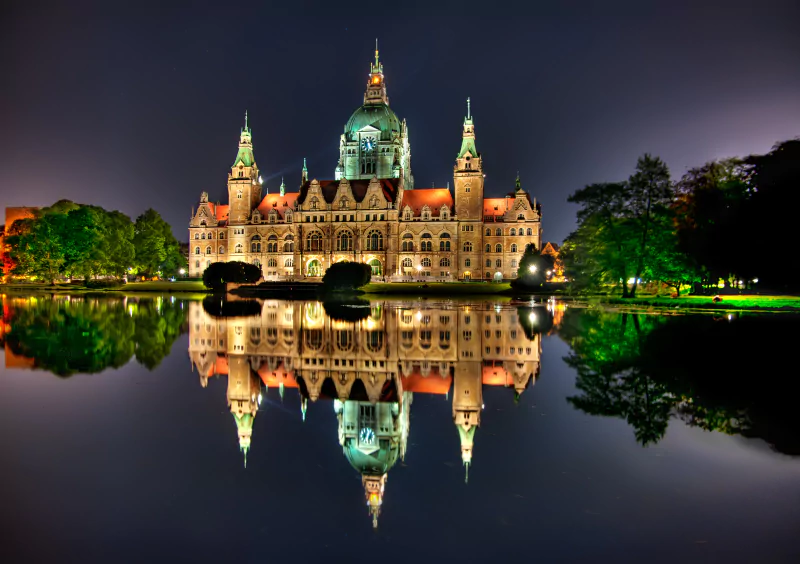 Illuminated man-made castle building at night in Phucket, reflected perfectly in the calm water below.