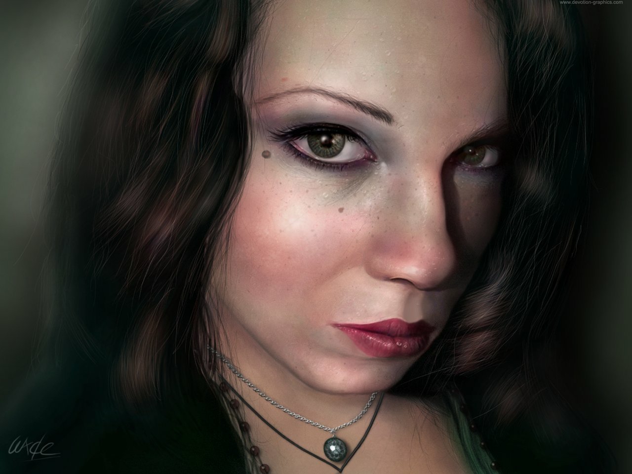 A close-up photograph of a woman with striking features, long dark hair, and bold makeup, capturing an intense and captivating expression.