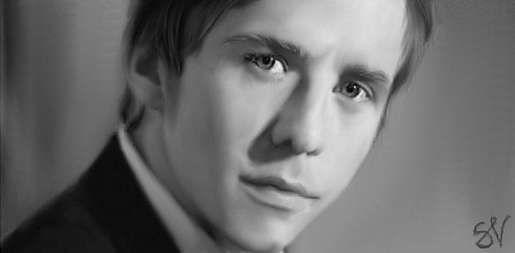 Black and white close-up portrait of man Danny Jones with a serious expression, softly lit against a blurred background.