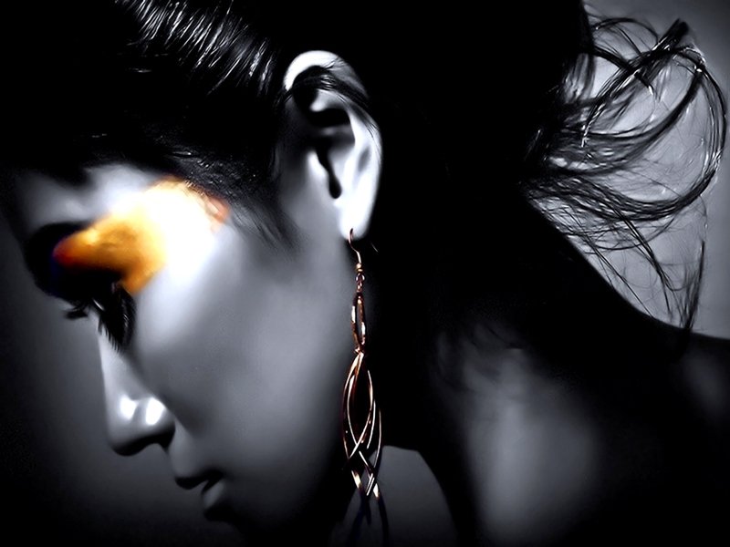 A side profile of a woman adorned with striking makeup and elegant earrings, set against a dramatic black-and-white background, evoking a captivating fantasy atmosphere.