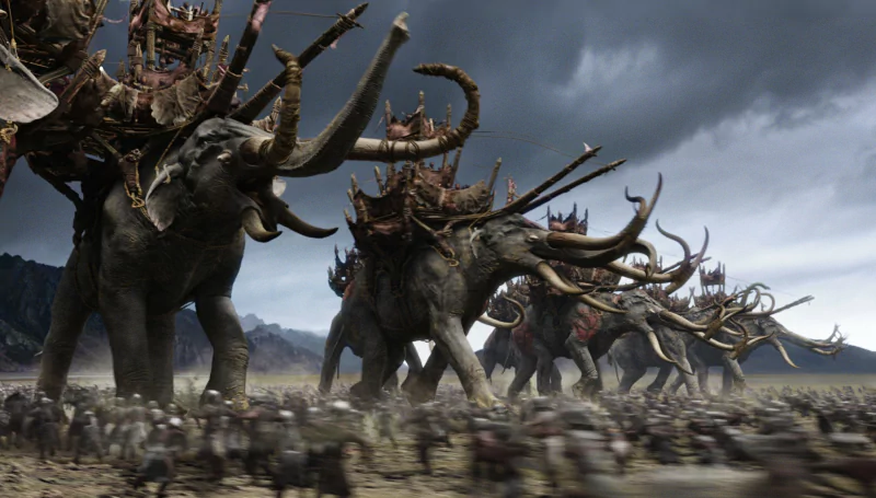 Epic battle scene from The Lord of the Rings featuring massive armored elephant-like beasts charging across a stormy battlefield.