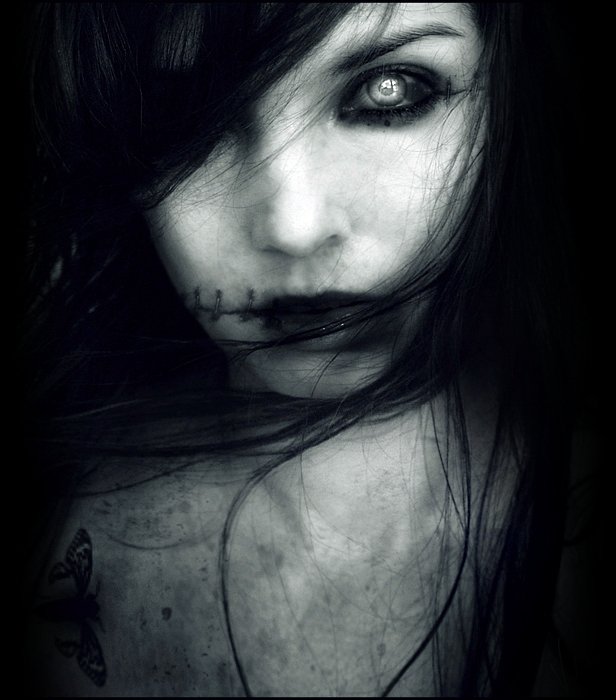 Close-up of a dark, eerie zombie face with pale skin, stitched lips, and haunting eyes, evoking a chilling, otherworldly atmosphere.