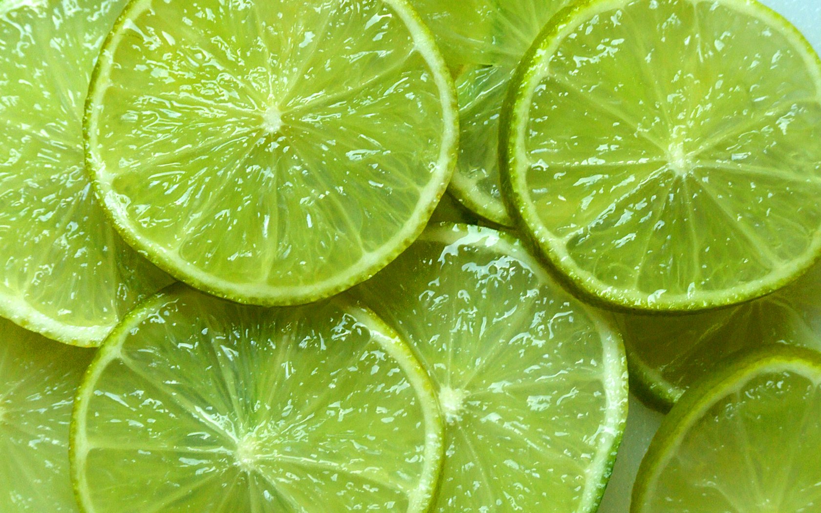 Close-up of fresh green lime slices arranged together, showcasing the juicy texture and vibrant color of the fruit.