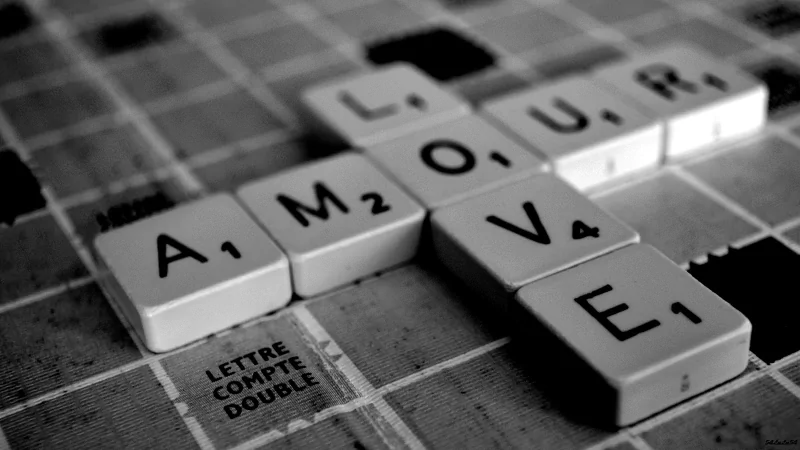 A black and white photograph of Scrabble tiles arranged to spell LOVE and AMOUR, capturing the essence of love in a creative and playful way.