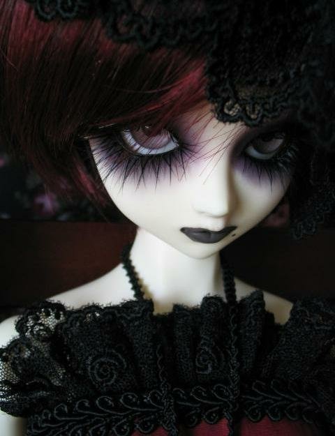 Close-up of a gothic doll with dark eye makeup, black lace attire, and a somber expression, evoking a moody atmosphere from a gothic TV show.