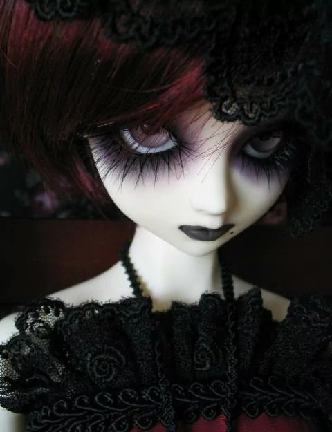 Close-up of a gothic doll with dark eye makeup, black lace attire, and a somber expression, evoking a moody atmosphere from a gothic TV show.