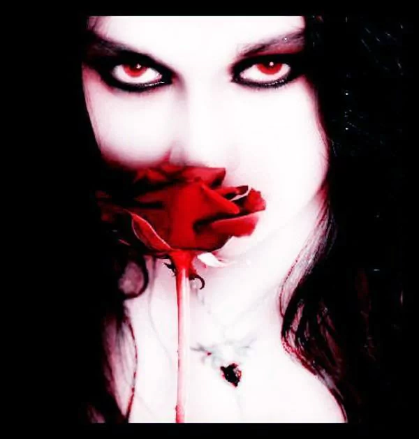 A dark, gothic portrait of a pale person with striking red eyes holding a vivid red rose close to their face, contrasting sharply with the black background and hair.