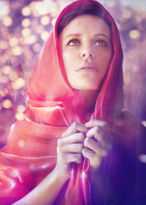 A woman in a vibrant pink and orange scarf gazes upwards, her hands gently clasped together, surrounded by a soft, ethereal glow. The photograph captures a moment of serene reflection.