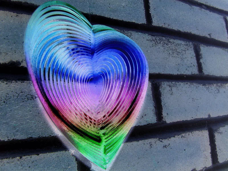 A vibrant, artistic heart design in swirling colors of blue, pink, and green, set against a textured brick wall, beautifully symbolizes love and creativity.