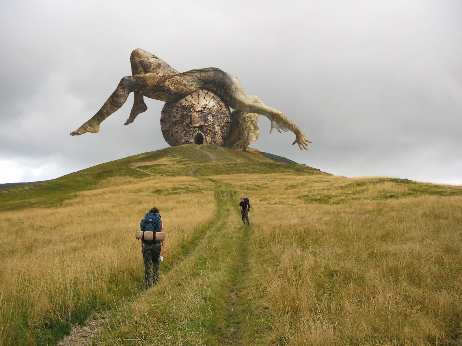 Artistic photography capturing two hikers approaching a massive, surreal sculpture of a reclining figure integrated with a large clock on a grassy hill under a cloudy sky.