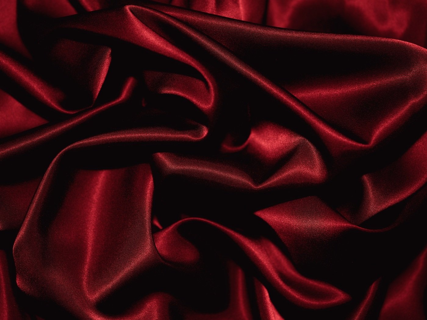 Smooth red silk fabric with abstract folds and gentle creases creating a rich, flowing texture.