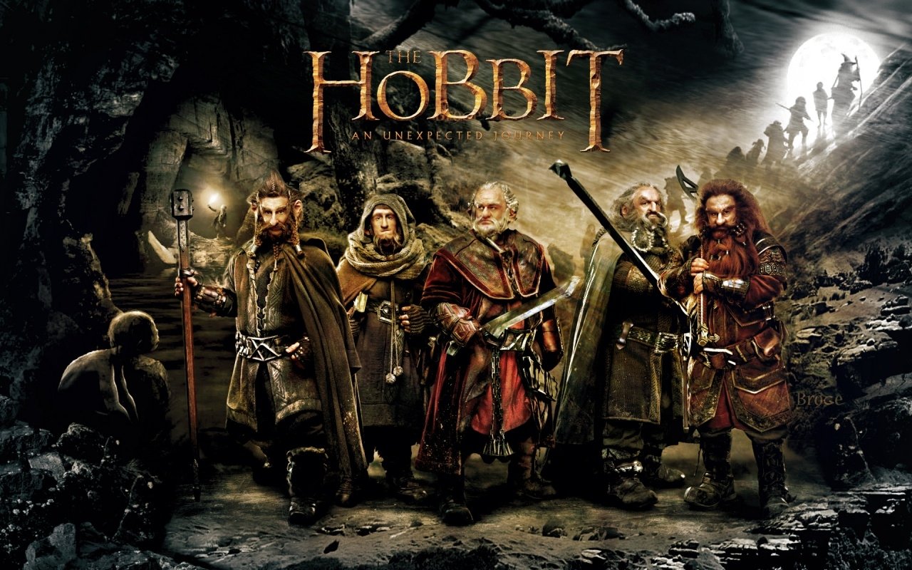 Promotional image for the movie The Hobbit: An Unexpected Journey featuring key characters standing in a dark, cavernous setting with the title above them.