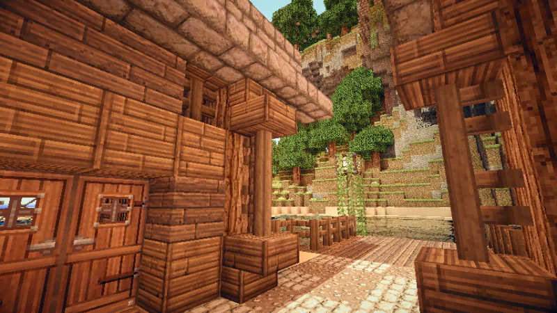 A cozy wooden structure in Minecraft, surrounded by lush trees and textured terrain, showcasing the game's distinctive blocky style and vibrant environment.