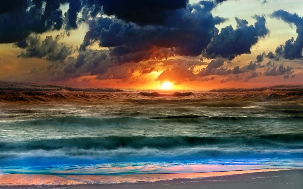 Artistic view of a vibrant sunset over the ocean, with waves gently rolling onto a beach under a dramatic sky filled with clouds.
