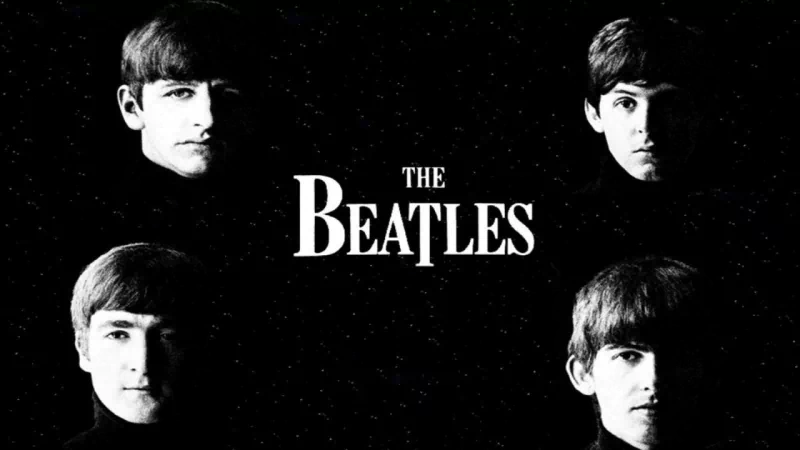 A black and white image featuring the four members of The Beatles, highlighting their iconic looks against a dark background. The band's name is prominently displayed.