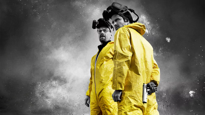 Two figures in yellow hazmat suits and respirators from TV show Breaking Bad stand against a smoky, monochrome background.