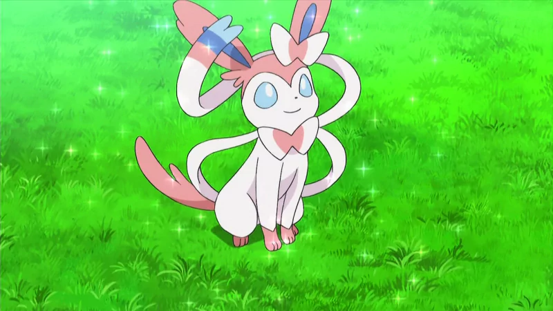 Sylveon, a Fairy-type Pokémon from the anime series, is depicted sitting on lush green grass, surrounded by sparkling lights, exuding charm and playfulness.