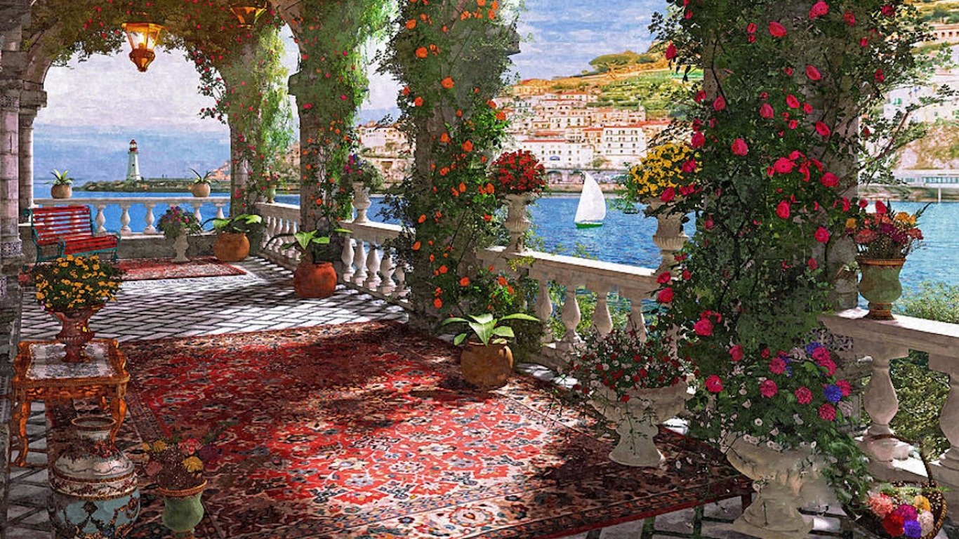 Artistic painting of a sunlit terrace adorned with vibrant flowers and lush greenery, overlooking a serene coastal town and sparkling blue waters.