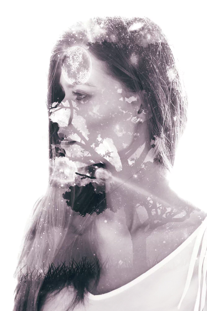 Artistic double exposure of a woman’s profile blended with tree branches and abstract light textures in soft monochrome tones.