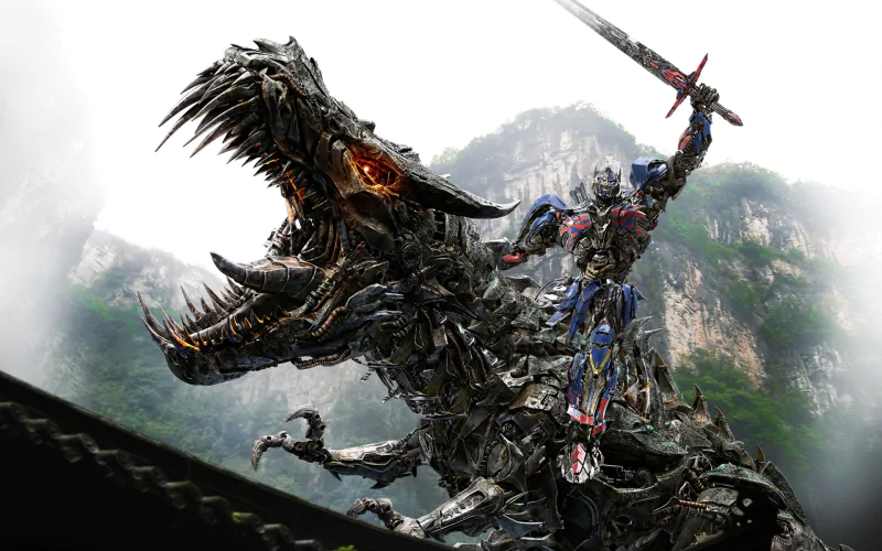A battle scene from the movie Transformers: Age of Extinction features a robot wielding a sword while riding a mechanical dragon against a mountainous background.