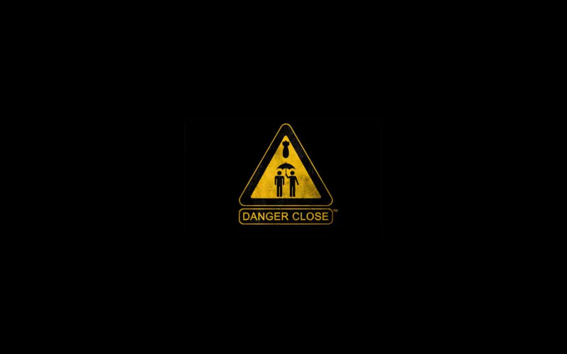 Misc sign: yellow triangular warning on black background showing two people standing close under an exclamation mark, labeled DANGER CLOSE.