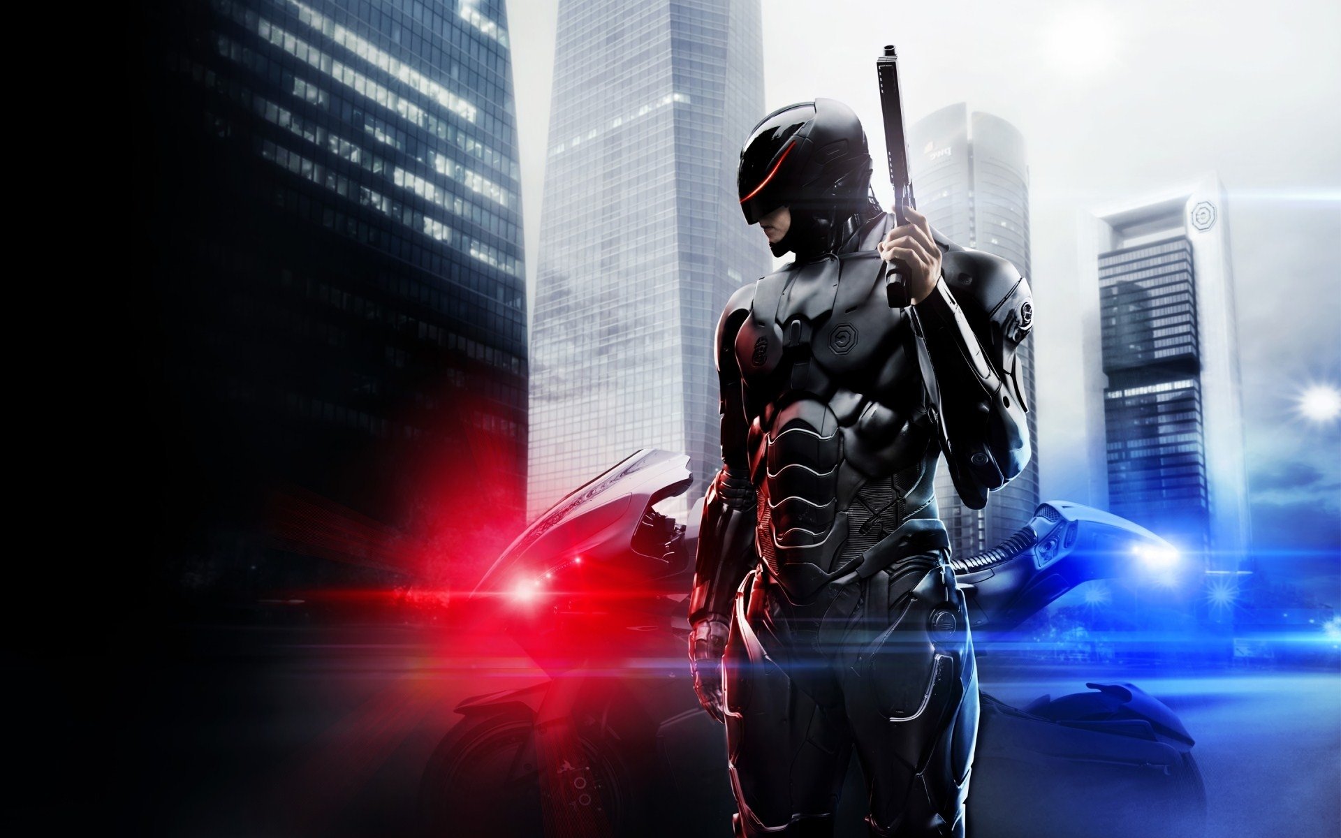 Robocop stands armed in front of a police car with flashing red and blue lights, set against a cityscape backdrop from the 2014 movie Robocop.