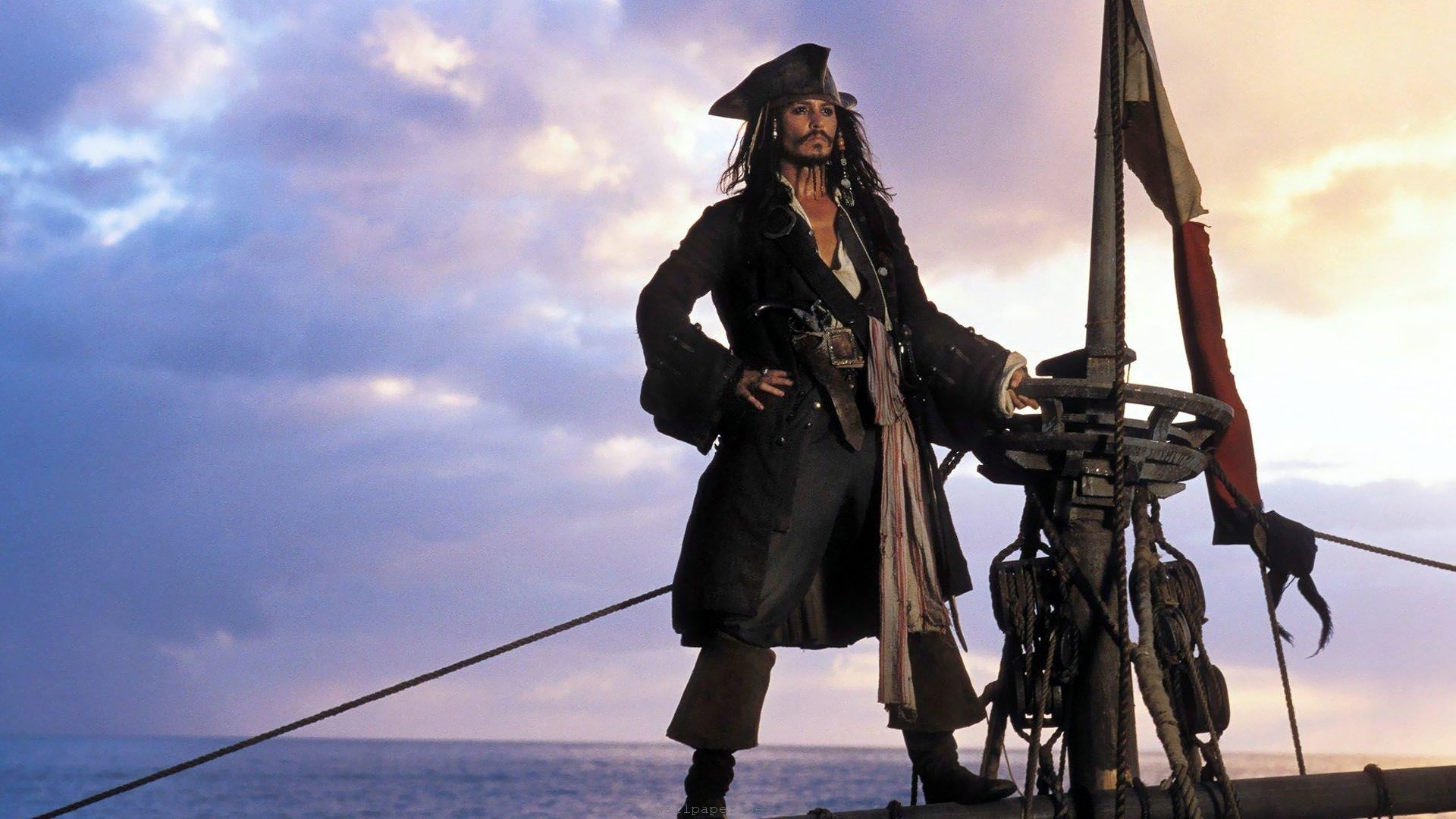 Captain Jack Sparrow stands confidently on the deck of a ship at sunset in a scene from the movie Pirates of the Caribbean: The Curse of the Black Pearl.