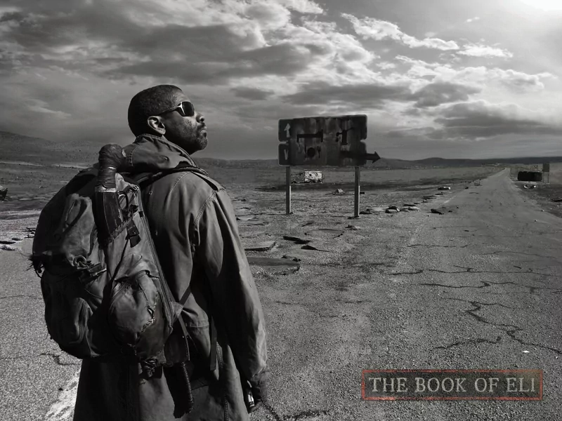 A lone man with sunglasses and a large backpack stands on a cracked road under a dramatic sky in a scene from the movie The Book of Eli.