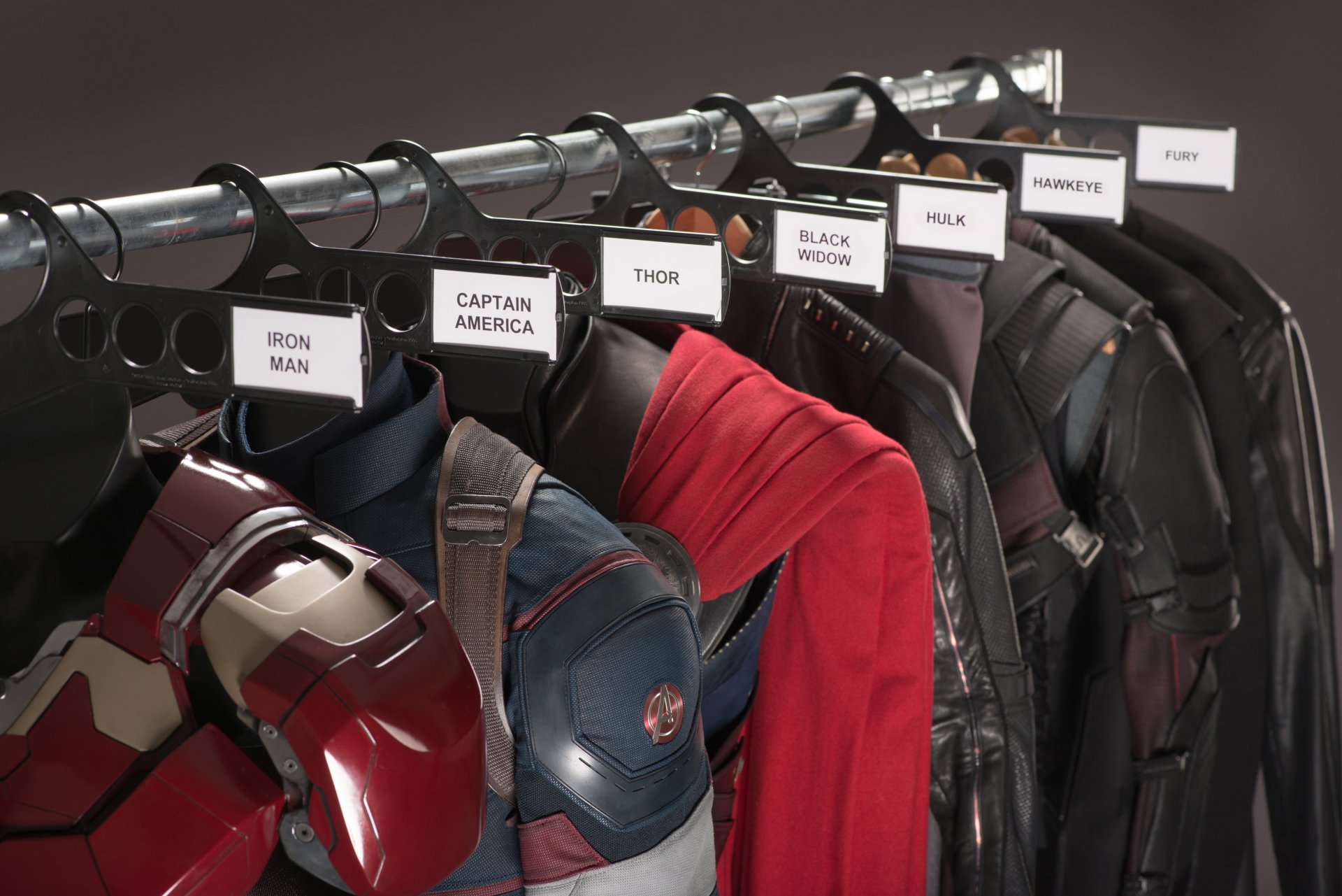 Costumes from *Avengers: Age of Ultron* hang on a rack, featuring iconic outfits labeled for Iron Man, Captain America, Thor, Black Widow, Hulk, Hawkeye, and Nick Fury.