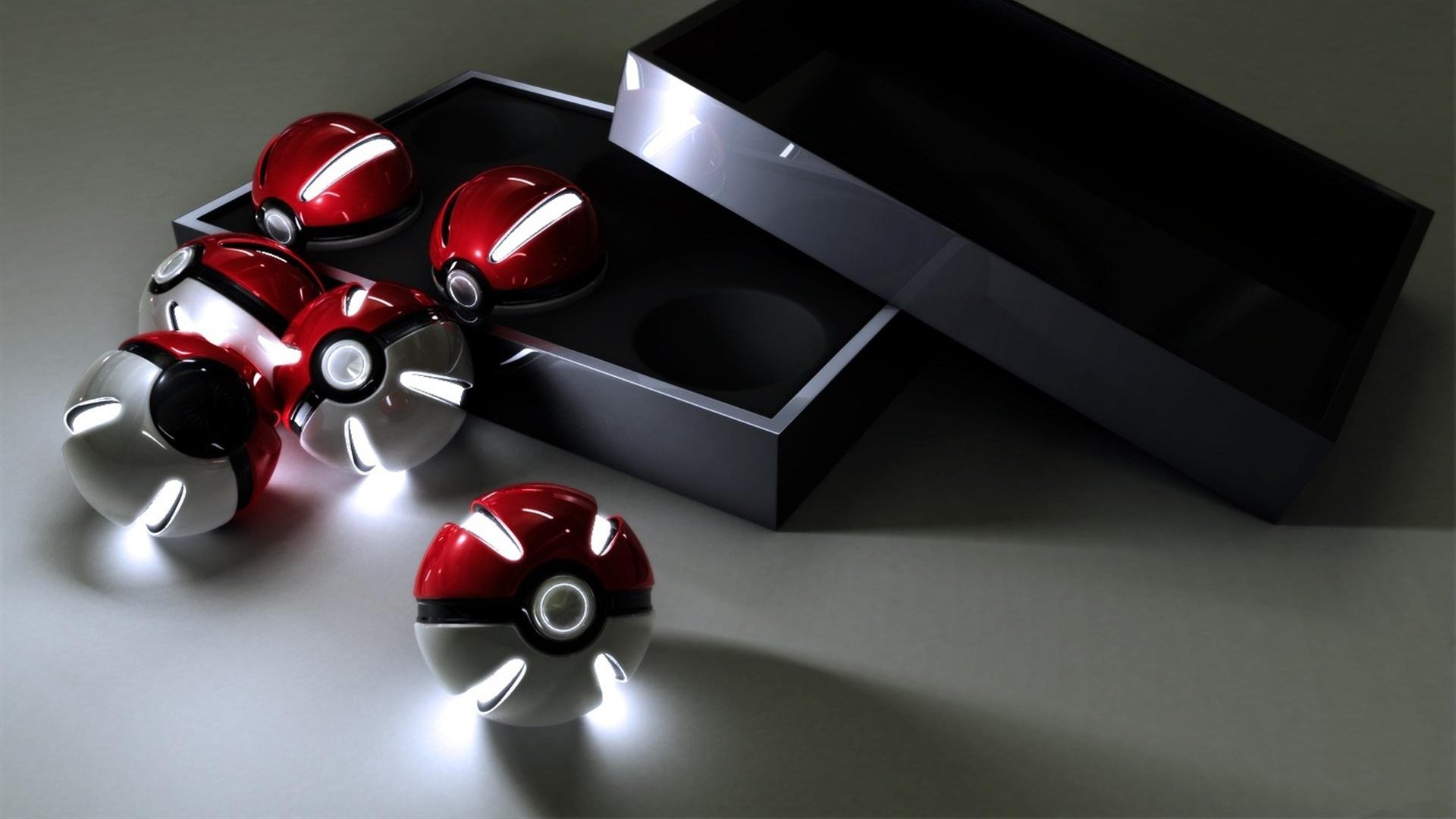 A set of illuminated Pokeballs from the Pokémon anime, displayed next to an open black box on a dark surface.