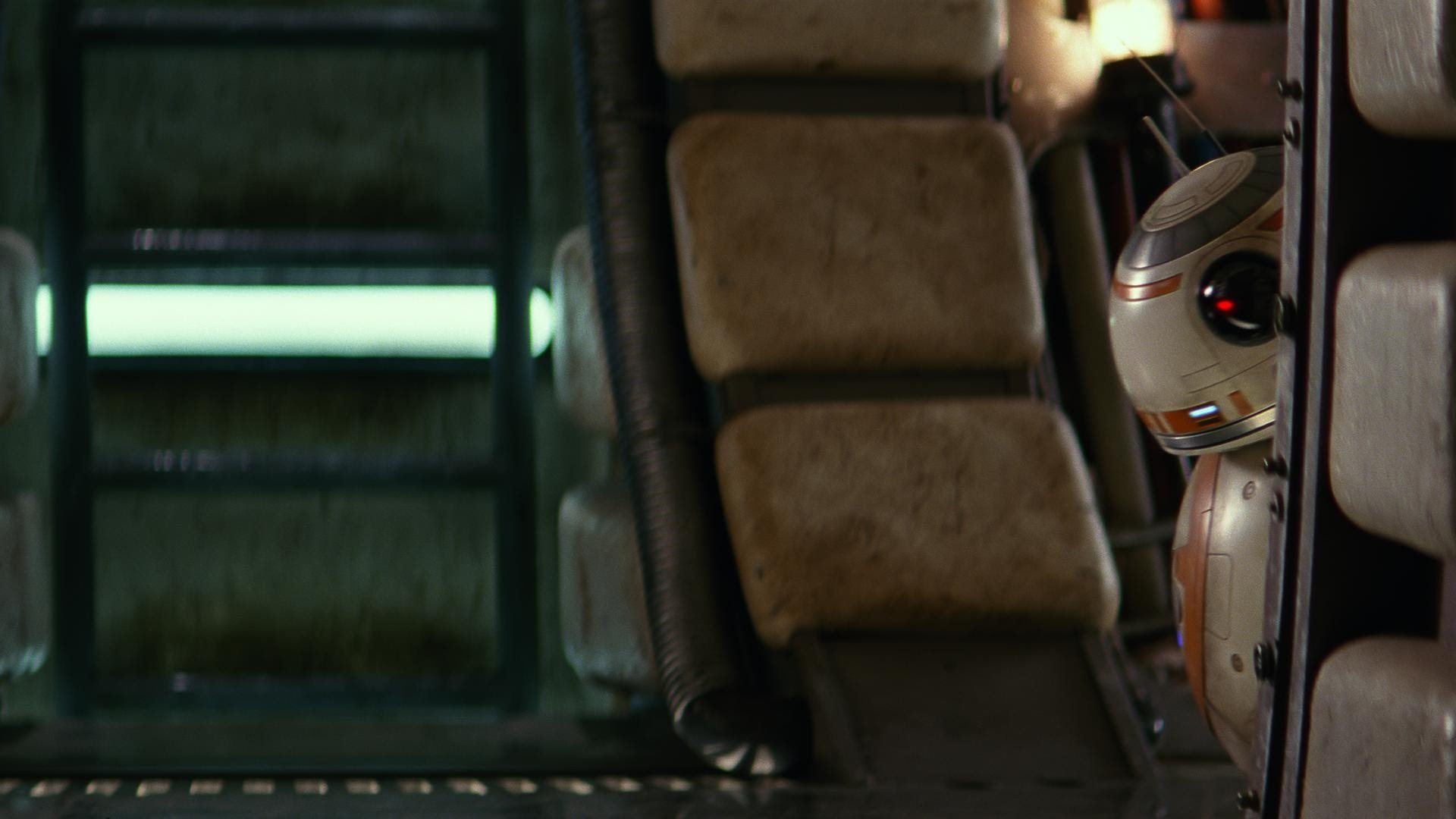 BB-8 peeks around cushioned ship panels inside the Millennium Falcon, a scene from the movie Star Wars Episode VII: The Force Awakens.