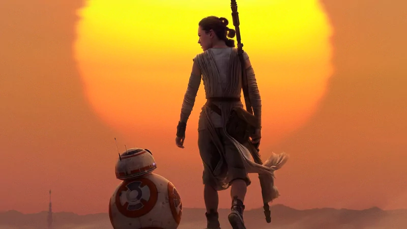 Rey and BB-8 walk together with a large setting sun in the background, a scene from Star Wars Episode VII: The Force Awakens.