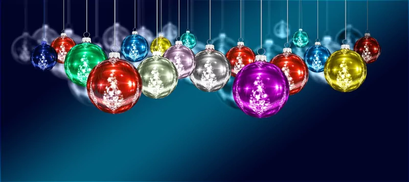 A festive display of colorful Christmas ornaments hangs against a deep blue background, showcasing vibrant hues of red, green, gold, blue, and purple, embodying holiday cheer.
